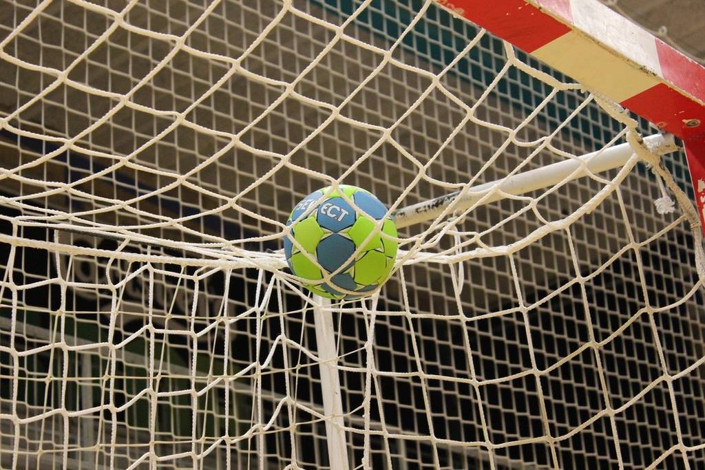 Bola sepak mengarah ke gawang berjaring di lapangan stadion