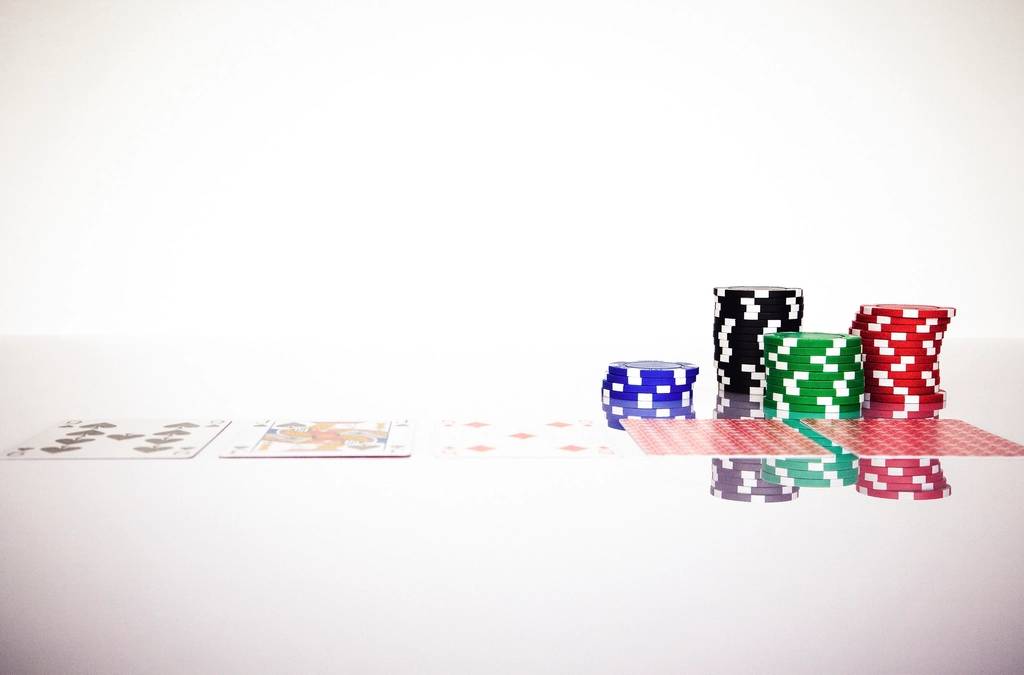 Tumpukan chip poker dan kartu remi di atas meja